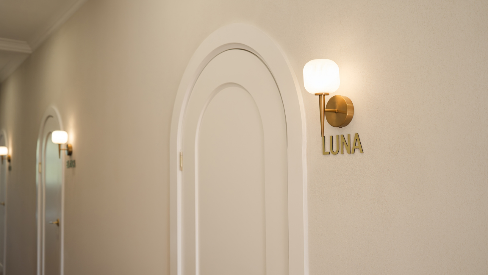 Decorative wall sconce with 'LUNA' on a beige wall