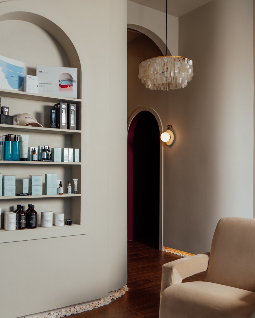 Modern interior with shelves displaying products, a chandelier, and a chair.