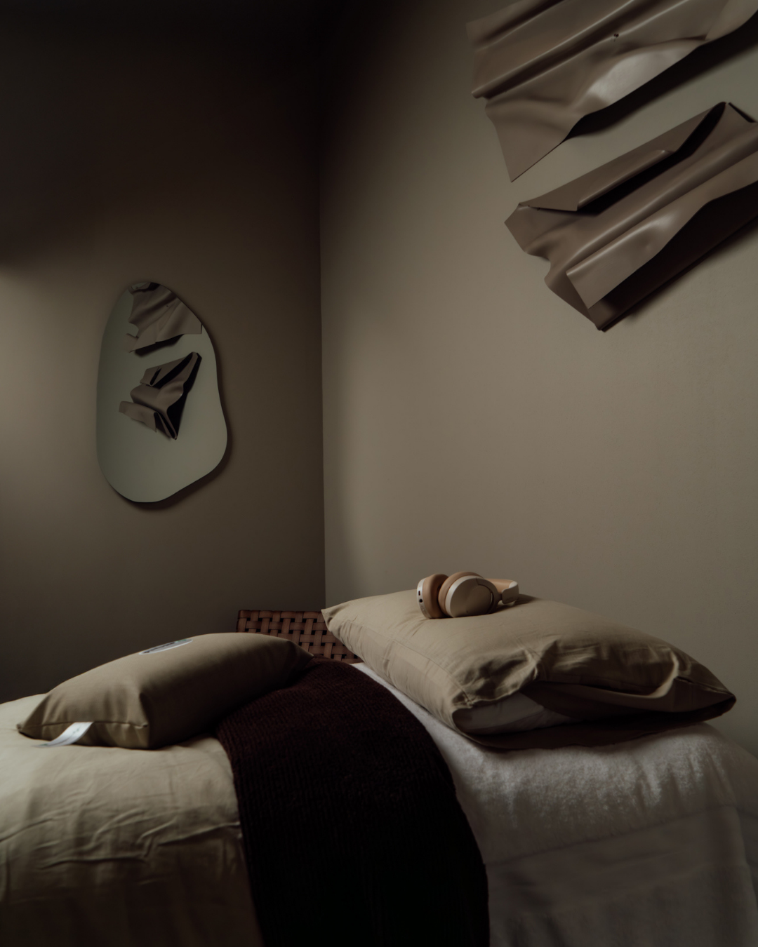 Bedroom with a bed and pillows against a wall with abstract art.