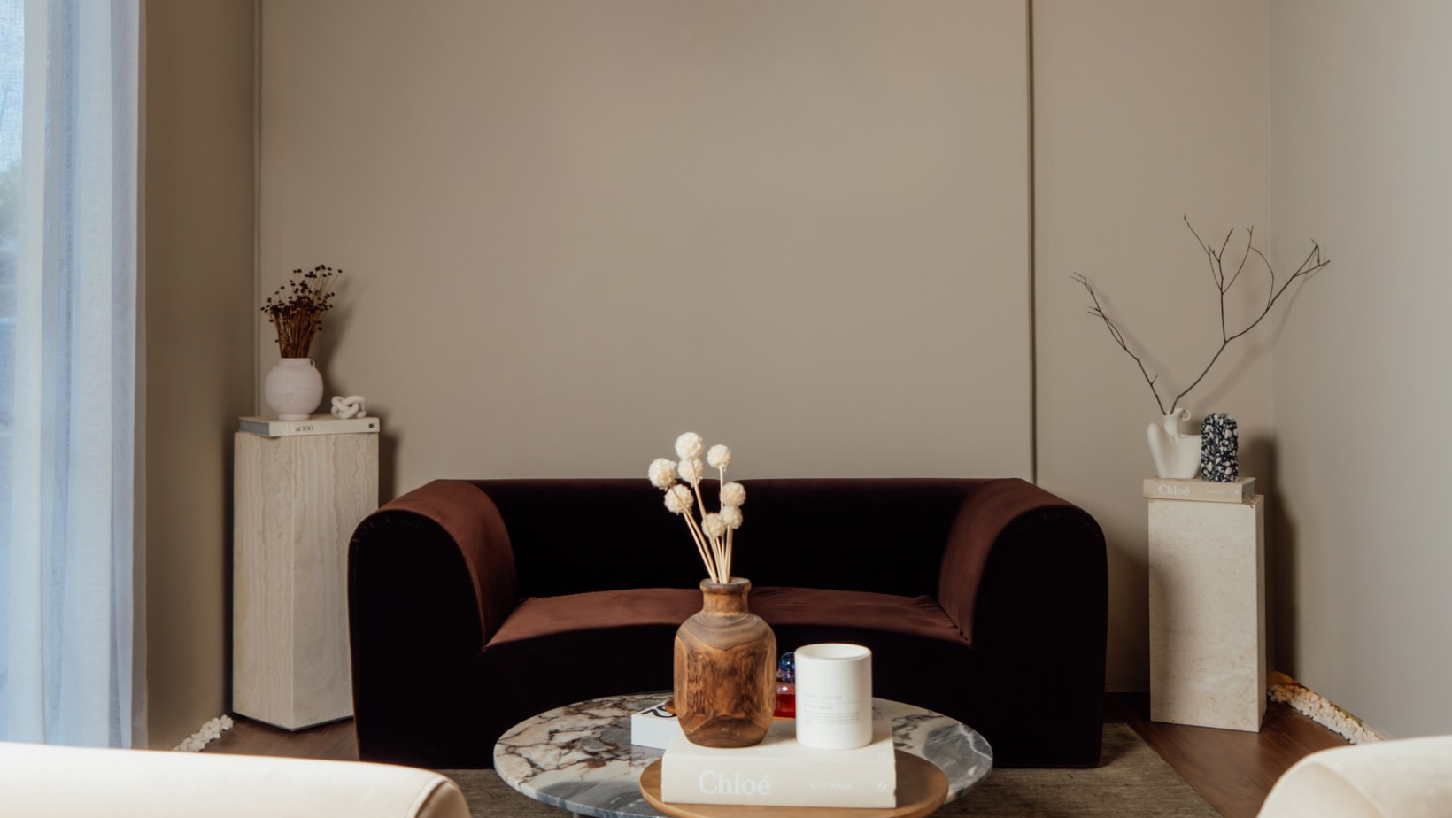 Modern living room with a brown sofa, coffee table, and decorative items.