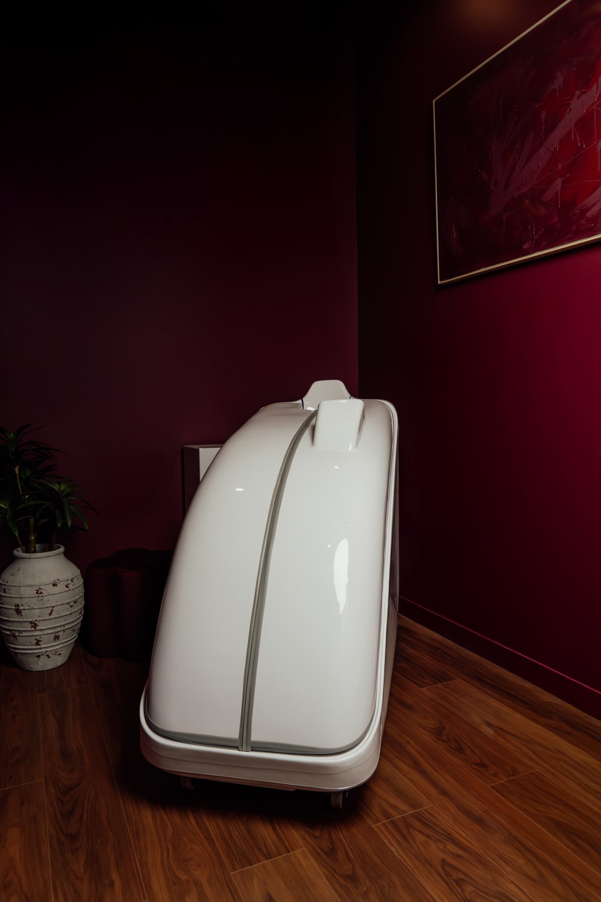 White suitcase on a wooden floor against a red wall